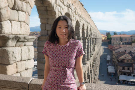 Attractive Asian girl during vacation in Spain - young happy and beautiful Korean woman visiting world heritage aqueduct in Segovia enjoying holidays travelの写真素材