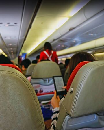 blurred peple playing her phone on the interior airplaneの写真素材