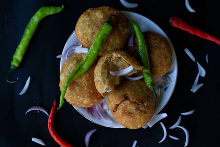 Tasty Indian snack kachori stacked on one another and served with green chillies and onions with a...