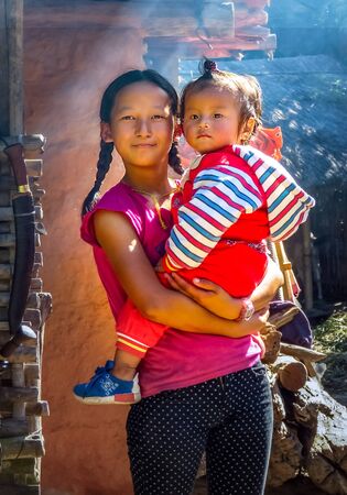 Gairi Pangma, Sankhuwasabha District, Nepal - 11/18/2017: Young girl with braids holding little brother boyのeditorial素材