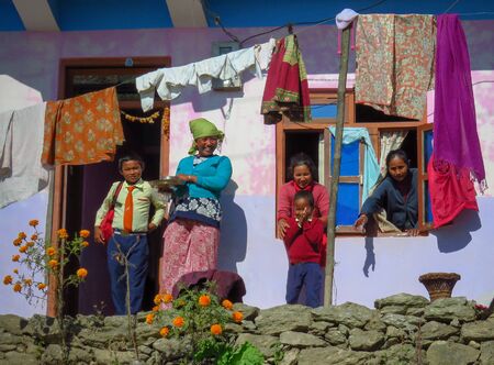 Gairi Pangma, Sankhuwasabha District, Nepal - 11/19/2017: Mothers and children on the porch outside the house, colorful clothes drying in the sunのeditorial素材