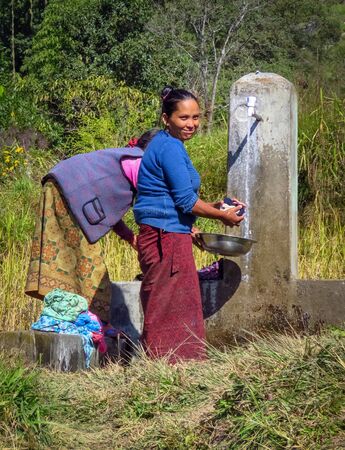 Gairi Pangma, Sankhuwasabha District, Nepal - 11/19/2017: Nepalese woman washing clothes at the water tap villageのeditorial素材