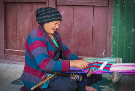 Num, Nepal - 11/17/2017: woman manually weaving a piece of cloth sitting on the ground in a small mountain village in East Nepal, Sankhuwasabha Districtのeditorial素材