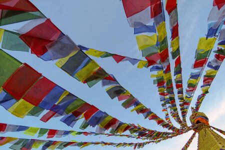 Colorful buddhist prayer flags swaying in the wind, attached to the top of Boudhanath stupa, Kathmandu, Nepalの写真素材