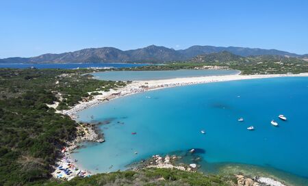 Panorama coastal view over sand beach, tranquil bay, distant mountains and blue water of the Mediterranean Sea, Porto Giunco, Sardinia, Italy, Europeの写真素材