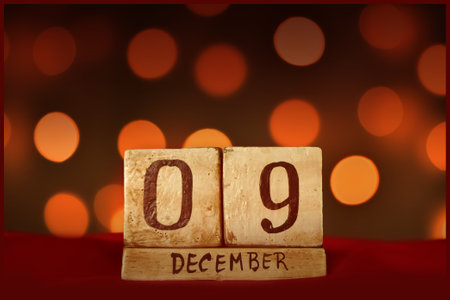 December 9 vintage wooden block calendar on red fabric, festive bokeh lights background greeting card celebrating holidays, birthday, save the date for special occasion.の写真素材