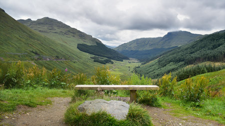 Viewpoint with bench overlooking Highland mountains and valley landscape. Scenic panorama on the way from Luss Loch Lomond to Inveraray, Travel Scotland, United Kingdom, Europeの写真素材