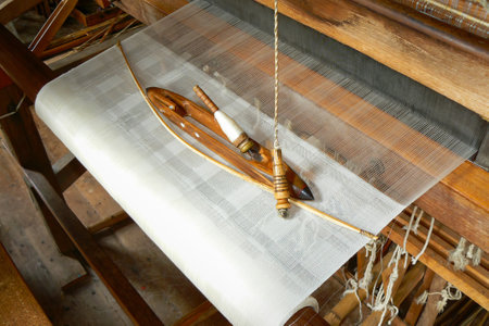 Weaving shuttle, spndle and yarn on loom. Warp and weave of white fabricの写真素材