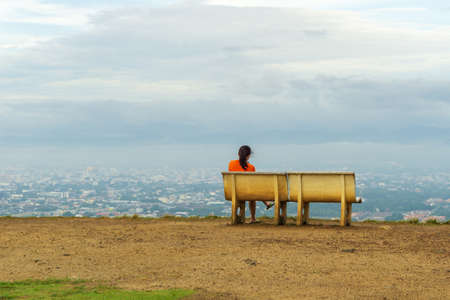A woman sitting alone on the mountain overlooking the cityの写真素材