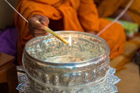 Buddhist monks, bowl with a candle and holy water 