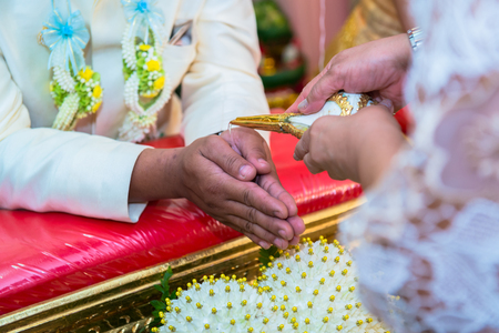 hands pouring blessing water into groom s hands, Thai wedding ceremonyの写真素材