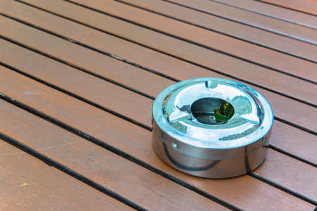 Metal ashtray on wooden table の写真素材