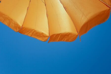 an orange umbrella over blue sky  の写真素材