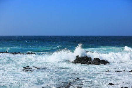 Cool waves crashing at Yongdam Beach in Jeju Islandの写真素材