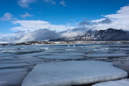 Ice floes with low hanging clouds at glacier Jökulsárlón in Iceland
