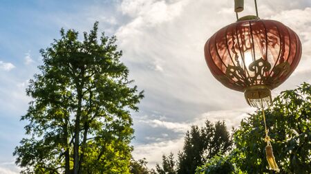 Red chinese lantern with golden ornaments illuminated by the sunの写真素材