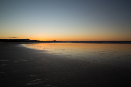 Orange and blue sky during the sunset at the beach with light reflectionsの写真素材