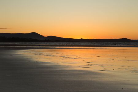 Orange and blue sky during the sunset at the beach with light reflectionsの写真素材