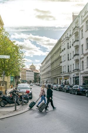 BERLIN, GERMANY - SEPTEMBER 26, 2018: Vertical view of two tourists with luggage crossing the street near the Neue Synagoge, a landmark of the jews history, located at Novalisstrasseのeditorial素材