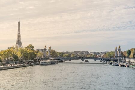 Beautiful postcard view of the Seine river crossing the Paris city in France, with tourist attraction boats in the margins at the eiffel tower and the Alexander III bridge in the backgroundの写真素材