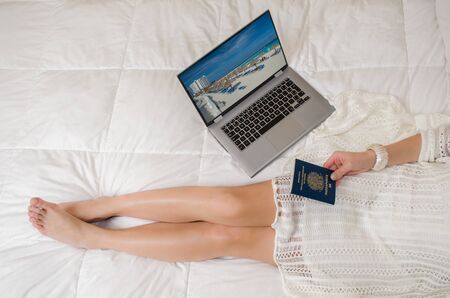 Woman planning holidays to the caribbean, in bed, passport in hand, seen from above.の写真素材