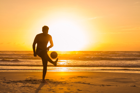 Great concept of soccer, man playing soccer on the beach in golden hour, sunset. Making keepie uppie.の写真素材