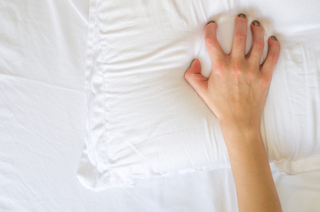 Hand orgasm of woman on white bed, Hand of female pulling white sheets in ecstasy, feeling and emotion conceptの写真素材
