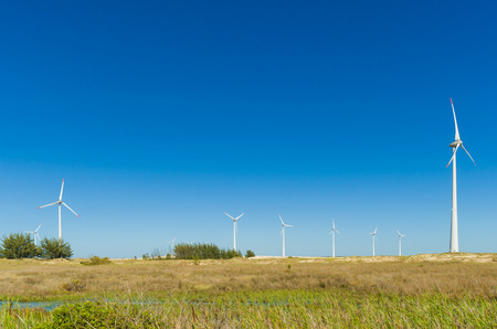 Great concept of renewable, sustainable energy. Wind field with wind turbines, producing aeolian energy under blue sky.の写真素材