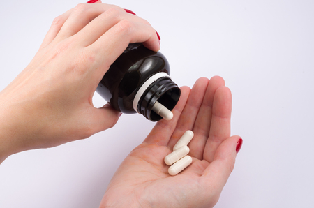 Woman hand turning medicine bottle in the palm of the hand. Doctor's prescription.の写真素材