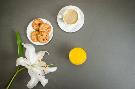 Breakfast from above with espresso, flower, juice of lajanra and cookies on gray table for various backgrounds.の写真素材