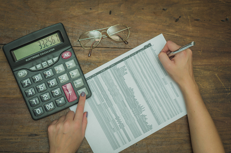 Woman hand calculating yields, calculator and chartの写真素材