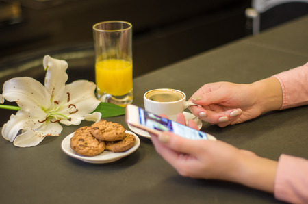Woman's hand having breakfast and interacting socially by cell phone.の写真素材