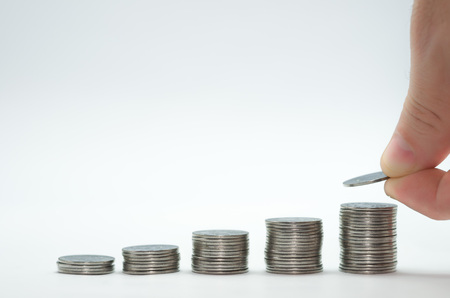 Great concept of savings, economy. Hand adding coin into pile of coins.