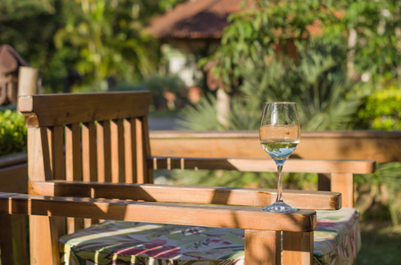 Glass of white wine in armchair on sunny dayの写真素材