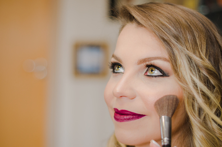 Makeup artist making up young blond woman with green eyesの写真素材