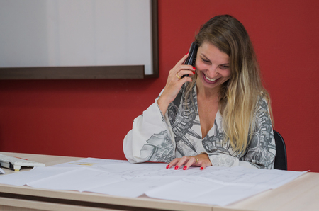 Great concept of working secretary, young woman talking on mobile phone in office.の写真素材