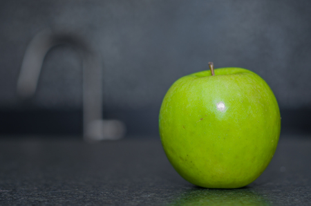 Green apple on black stoneの写真素材