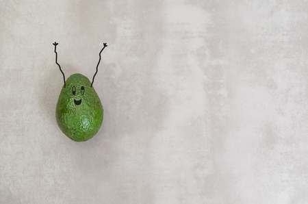 Great concept of healthy eating, avocado with happy face and arms upwards in gray background.の写真素材