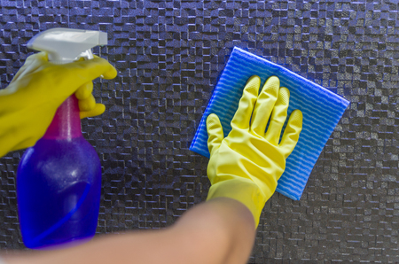 Great home cleaning concept, glove hand wiping tile wall.