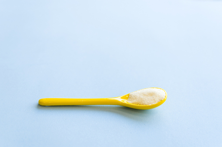 Spoon with sugar close-up on a light blue backgroundの写真素材
