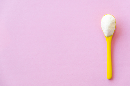 Spoon with sugar close-up on a pink backgroundの写真素材