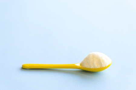 Spoon with sugar close-up on a light blue backgroundの写真素材