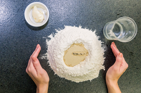 Woman preparing pizza dough on black granite table