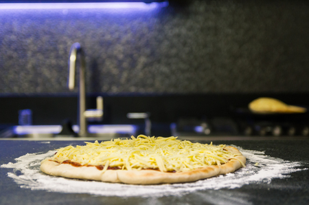 Preparing pizza, close-up of pizza dough with tomato sauce and mozzarella cheese.の写真素材
