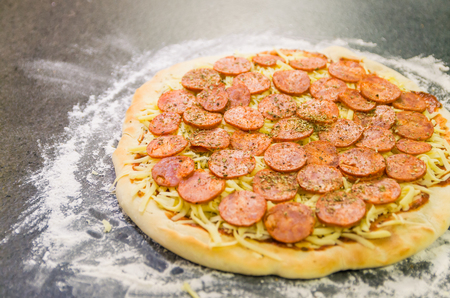Preparing pepperoni pizza on black granite tableの写真素材