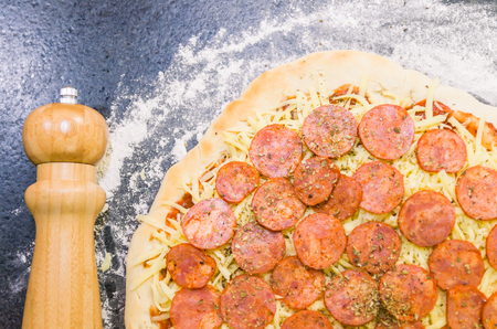 Preparing pepperoni pizza on black granite tableの写真素材
