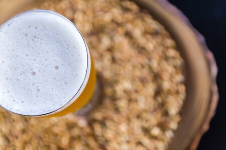Glass of beer viewed from above with malt in the background