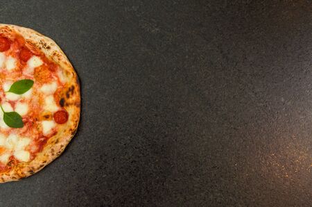 Great background for culinary themes, handmade pizza with marguerite flavor on black granite background with different ingredients.の写真素材