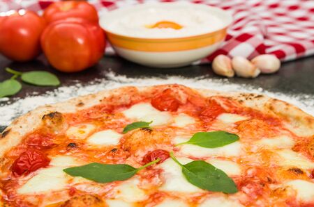 Great background for culinary themes, handmade pizza with marguerite flavor on black granite background with different ingredients.の写真素材