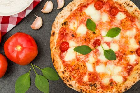 Great background for culinary themes, handmade pizza with marguerite flavor on black granite background with different ingredients.の写真素材